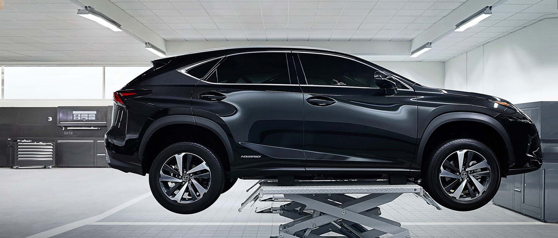 Tmavý osobní automobil na zvedáku v servisní dílně
